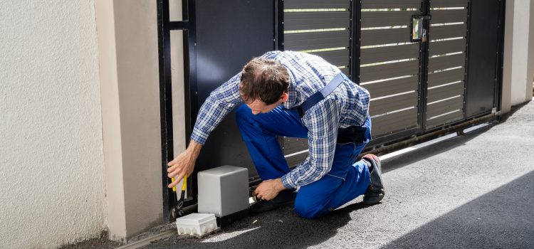 Electritian crouched down repairing the electric box on an automatic driveway gate